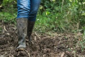 close-up of a latin peasant woman, walking along a muddy road in her marsh boots. girl on her way home through a wasteland. exploring nature.