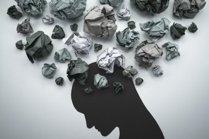 Concept image of anxiety and negative emotion. Waste paper and head silhouette.