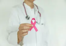 Zakaj se rak lahko ponovno vrne in kako ga skušajo ustaviti? Doctor woman with pink ribbon, supporting symbol of breast cancer awareness