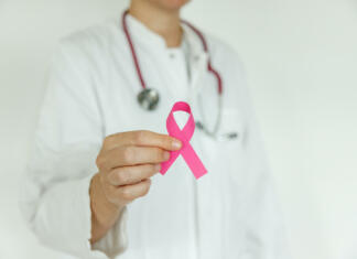 Zakaj se rak lahko ponovno vrne in kako ga skušajo ustaviti? Doctor woman with pink ribbon, supporting symbol of breast cancer awareness