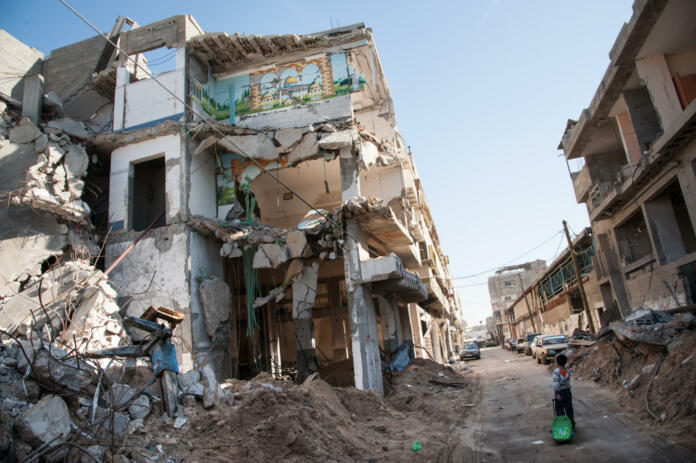 Gaza City, Occupied Palestinian Territories - December 2, 2012: A child passes a bombed-out residential block in the Al-Zeitoun neighborhood of Gaza City.