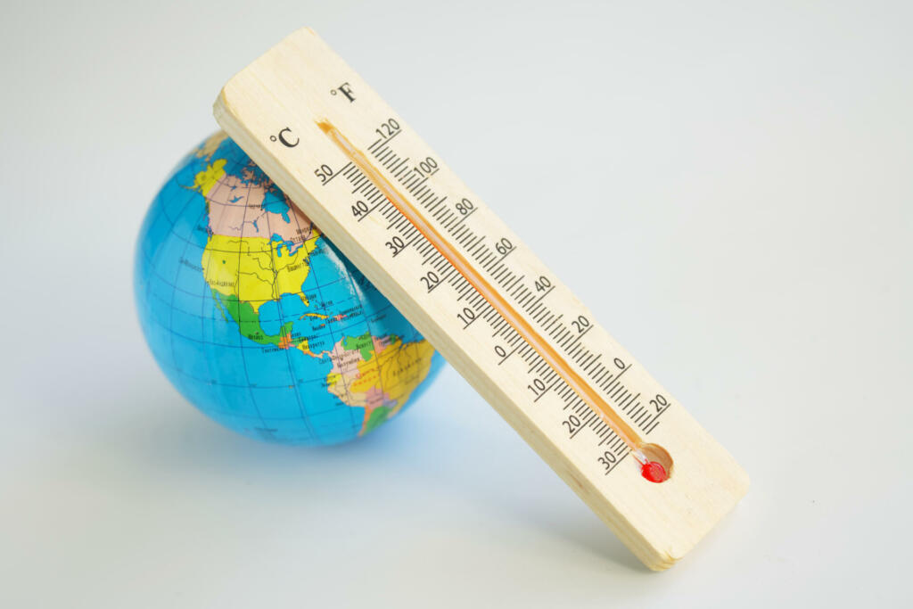 Globe and wooden eco-friendly thermometer on a white background. Temperature in Celsius and Faradays. Concept of climate change and global warming. Copy space. Selective focus. Close-up
