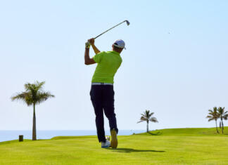 Golf: šport za bogate ali tudi za povprečnega študenta? Golfer on a golf course, ready to tee off. Golfer with golf club hitting the ball for the perfect shot.