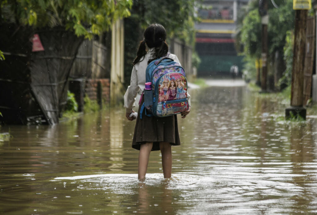 Guwahati, India. 25 May 2022. A girl returns from school wades across a flooded street after heavy rains, in Guwahati. Waterlogging is a common scene in Guwahati city due to poor drainage system.
