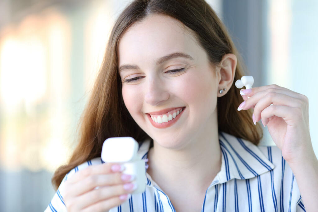 Happy woman putting earbud in the street