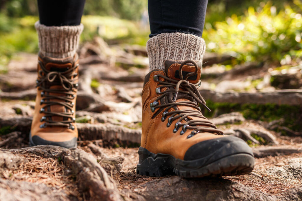 Hiking boot. Legs on mountain trail during trekking in forest. Leather ankle shoes