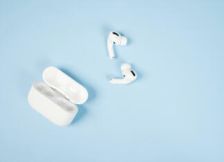 Slušalke buds: Prednosti, slabosti in vodič po nakupu Modern wireless bluetooth headphones with charging case on a blue background.