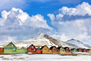 Row of colourful wooden houses in Longyearbyen, Svalbard, the most northerly town in the world. Early spring scene with snow on the mountains and the foreground.