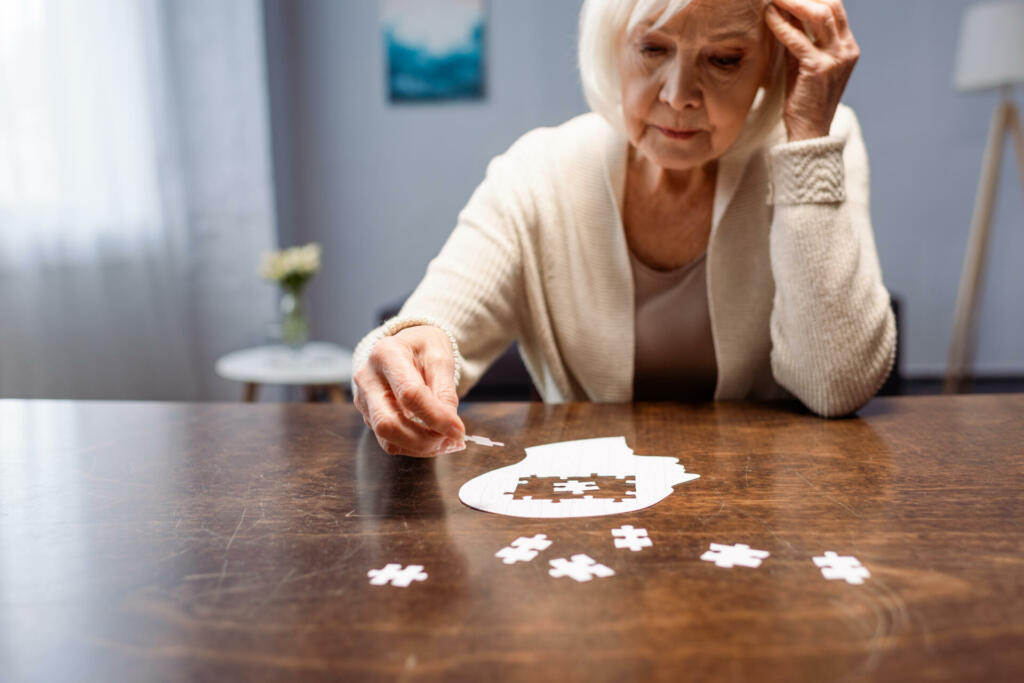 senior woman combining jigsaw puzzle for dementia rehabilitation