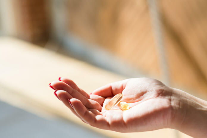 Spring vitamin defficiency. Woman hand holding fish oil supplement.