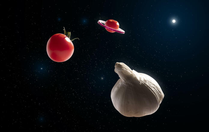 Universe of vegetables that look like planets in space. Tomatoes, onions and garlic, Mediterranean recipe ingredients in deep space illuminated by a star, universe of foods and tastes