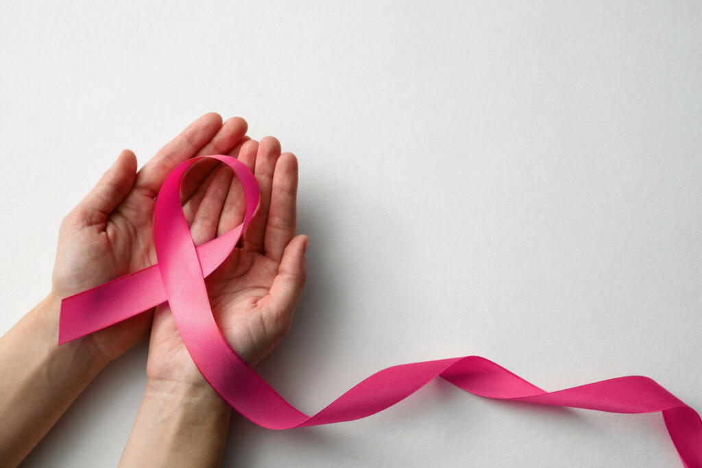 Woman holding pink ribbon on white background, top view with space for text. Breast cancer awareness concept