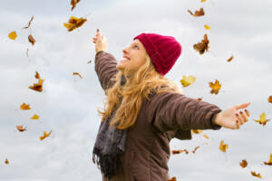 Young, happy woman with raised arms in autumn