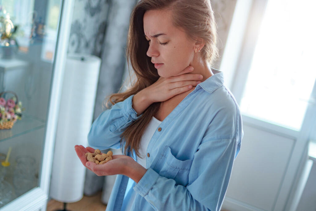 Young sick upset woman suffers from choking and cough from allergic reaction from peanut. Danger of nuts food allergy