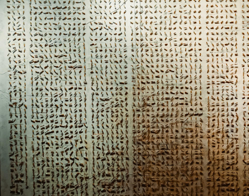 An aged parchment paper featuring archaic handwriting is situated in front of a traditional window shutter