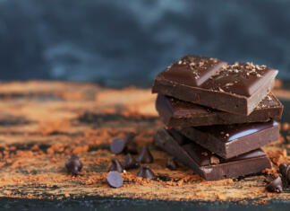 Preprosti recepti za sladice iz vroče čokolade Bitter chocolate stack with chocolate flakes, drops and cocoa powder on dark background