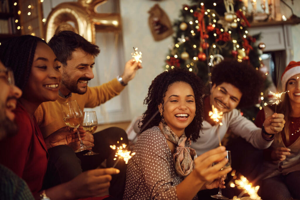 Cheerful friends having fun with sparklers during Christmas party at home.