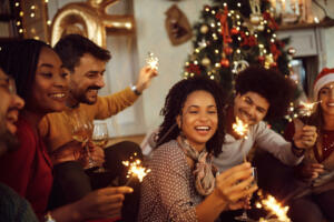 Cheerful friends having fun with sparklers during Christmas party at home.