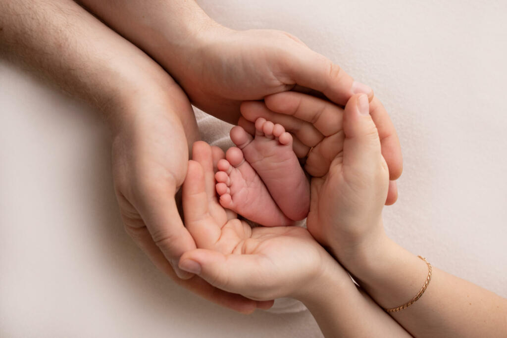 Children's legs in the hands of mother, father, parents. Feet of a tiny newborn close up. Mom and her child. Happy family concept. Beautiful concept image of motherhood stock photo.