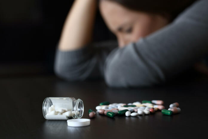 close-up-of-a-depressed-woman-beside-a-lot-of-pills-on-a-table-on-a-dark-background-stockpack-istock Depresija in ketamin