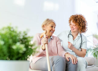 Nov začetek za obolele s Parkinsonovo? So odkrili rešitev? Friendly relationship between smiling caregiver in uniform and happy elderly woman. Supportive young nurse looking at senior woman. Young caring lovely caregiver and happy ward