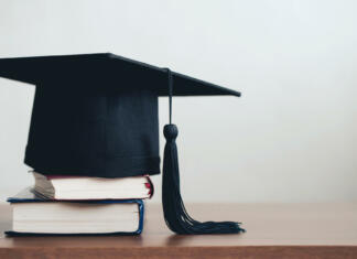 Kako pripraviti diplomo: koraki do popolne zaključne naloge graduation cap on a stack of books with empty space to the right.Graduation concept
