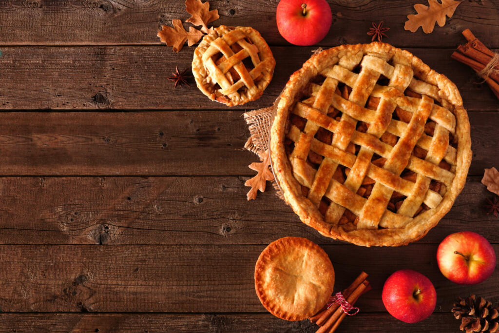 Homemade autumn apple pie corner border. Top view table scene over a rustic wood background with copy space.