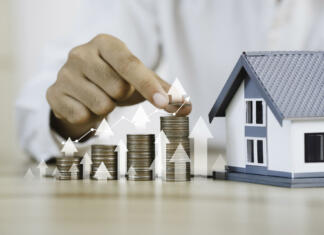 Ali je to prihodnost najemnin? House model and coin holder money on the table for finance and banking concepts. Property investment mortgage and home rental concept earning from home