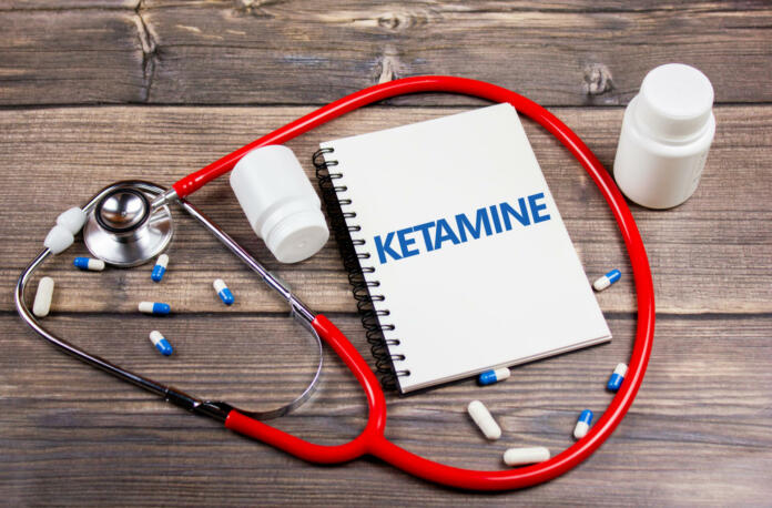 Inscription KETAMINE on the notepad next to the pills. Ketamine is on the table.