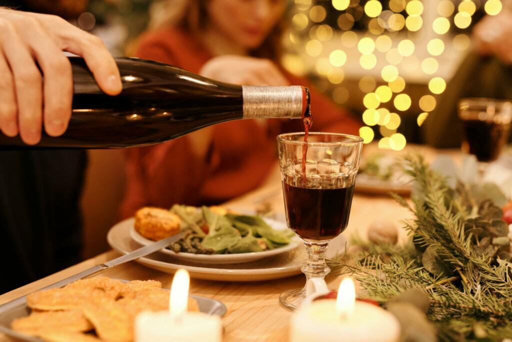 Person pouring wine on clear drinking glass