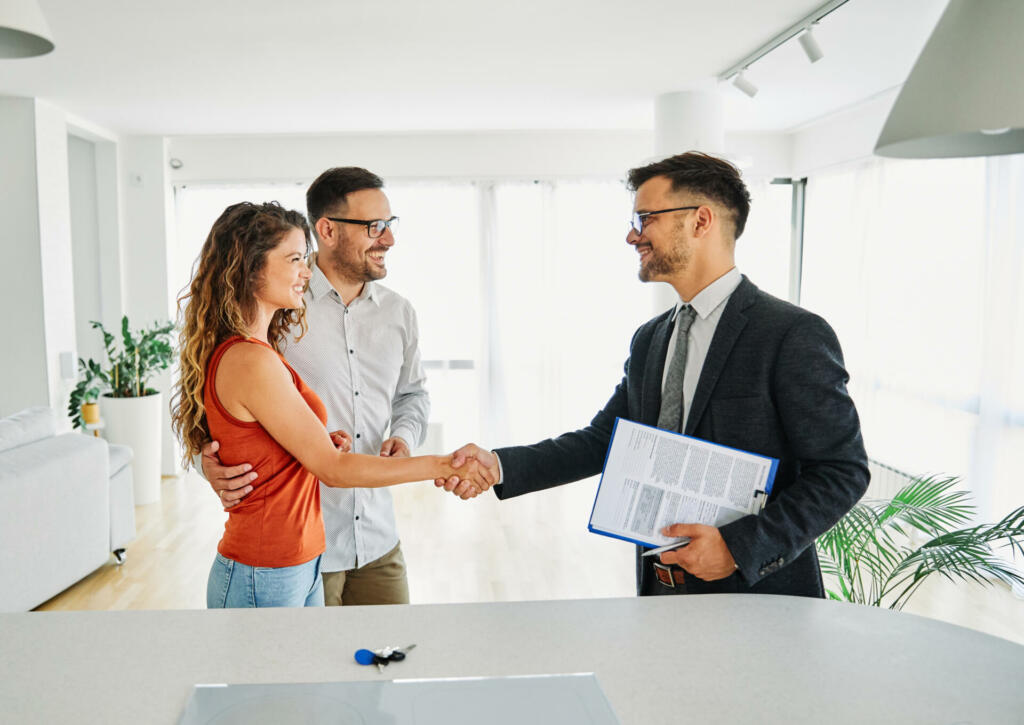 Real estate agent with couple shaking hands closing a deal