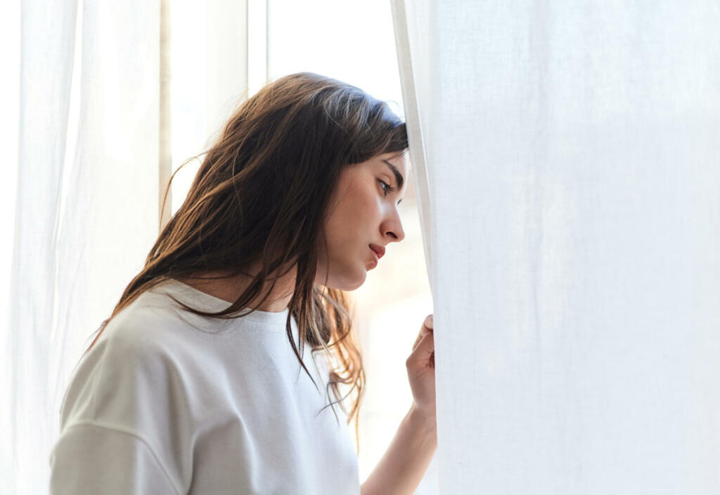 Sad young woman crying in her bedroom at home. Mental health concept.