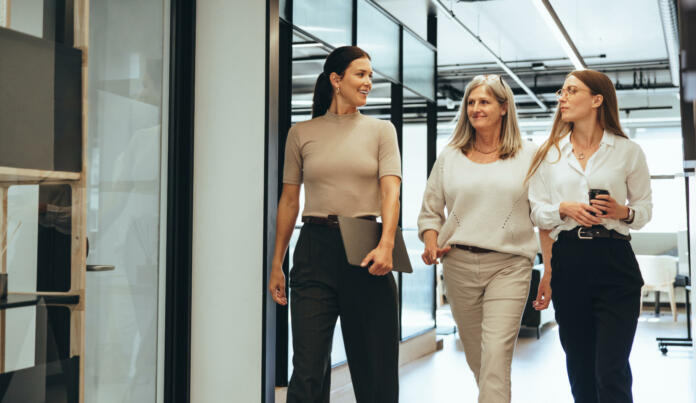 Three cheerful businesswomen walking together in an office. Diverse group of businesswomen smiling while having a discussion. Successful female colleagues collaborating on a new project.