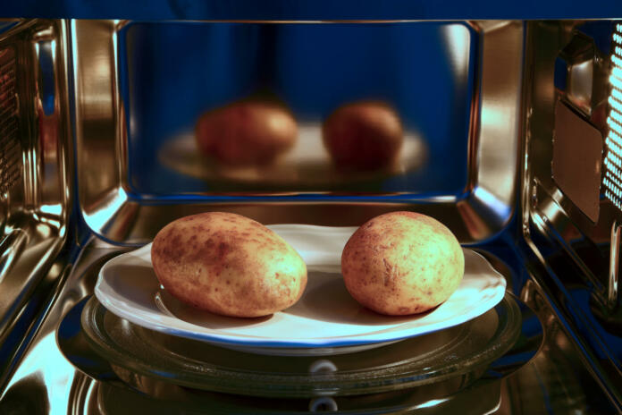 Two baked potatoes ready to cook in a microwave oven