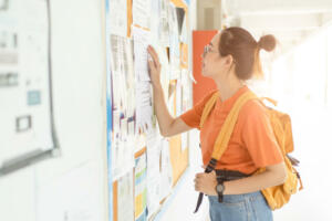 Unemployed young university woman looking for work or job after graduation at the post board