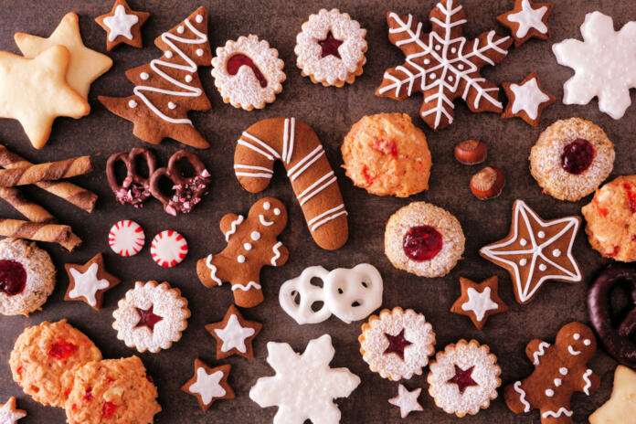 Variety of Christmas cookies and sweets. Top view over a dark stone background. Holiday baking concept.