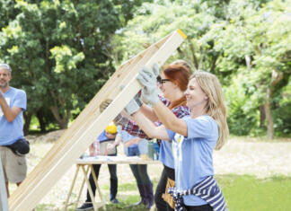 10 koristi prostovoljstva in vračanja: zate in tvojo skupnost Volunteers lifting construction frame at construction site