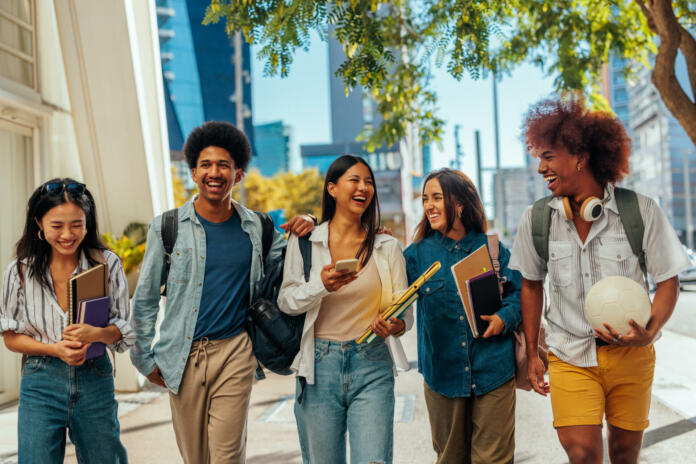 A group of young stylish students are walking together on the city streets having fun together.