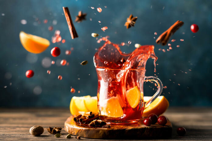 A splash of hot mulled wine with oranges, cranberries and spices in a glass. A traditional warming drink for the autumn-winter season. Stock image