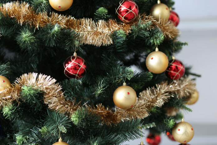 Artificial Christmas tree decorated with red-gold balls and tinsel. New Year decor concept