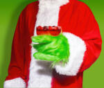 Christmas Grinch with Green Hands Making a Holiday Toast with a Cranberry Cocktail