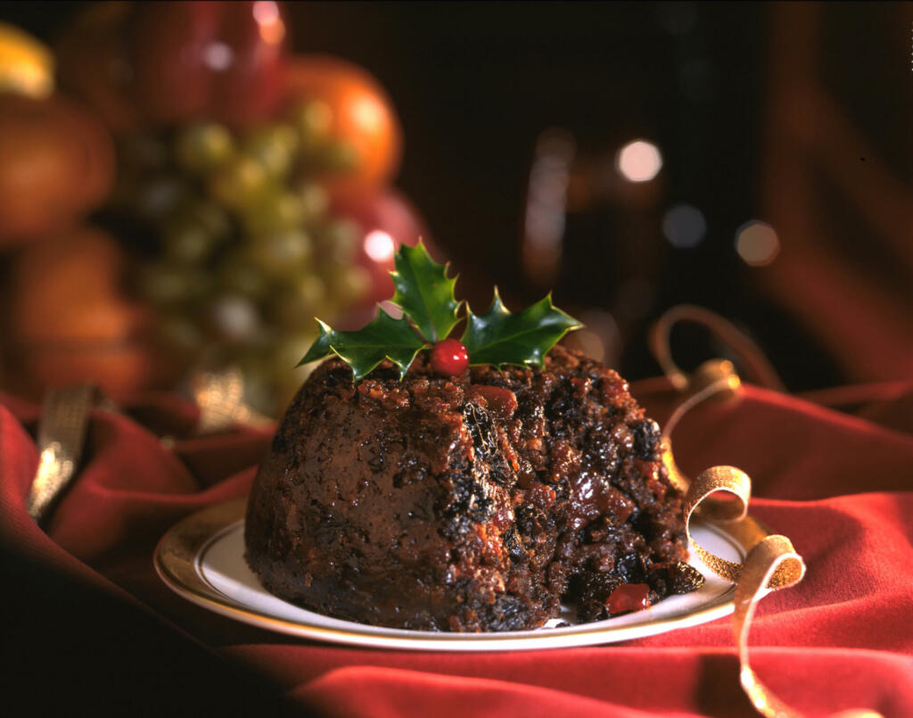 Christmas Pudding decorated with holly leaves on red background