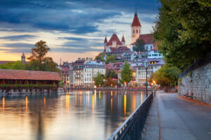 Cityscape image of beautiful city of Thun with the reflection of the city in the Aare river at sunset.