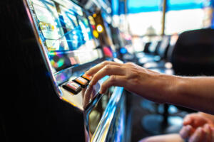 Closeup of Gambler Pressing the Spin Button While Playing Slot Machine in the Casino. Gambling Industry Theme.