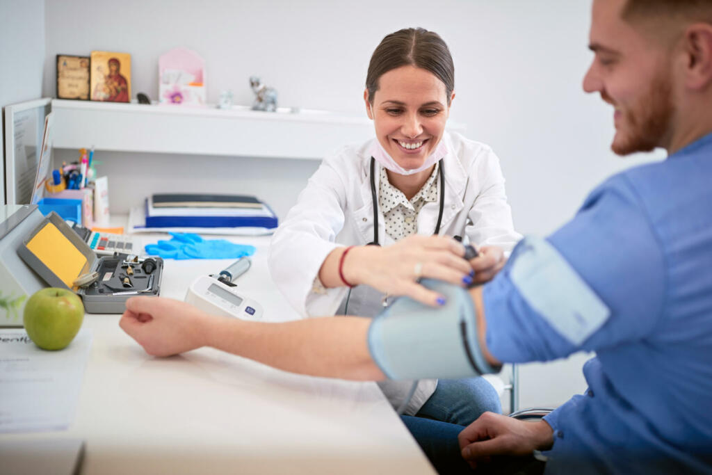 Female doctor attaches cuff from blood preasure aparatus on patients arm