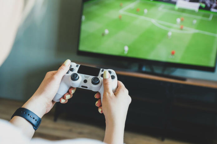 Girl playing a video game console. Game is football. Joystick in hands. Selective focus