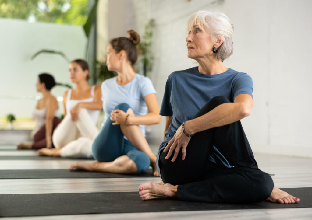 Group of sporty people practicing various yoga positions during training indoors