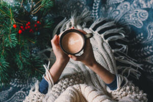 Hands holding hot cup of coffee. Hygge background. Christmas mood.