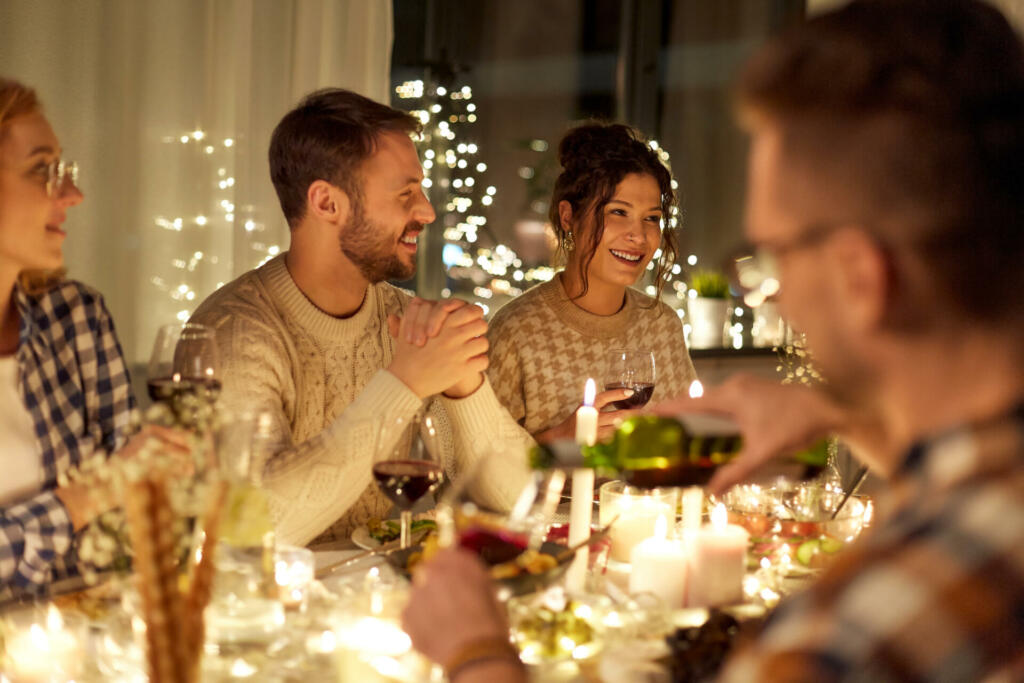 holidays, celebration and people concept - happy friends having christmas dinner party and drinking non-alcoholic red wine at home