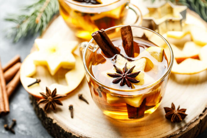 Hot drink for New Year, Christmas or autumn holidays. Mulled cider or spiced tea or mulled white wine with lemon, apples, cinnamon, anise, cloves.